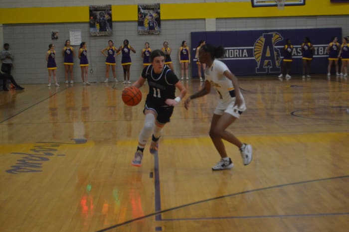 St. Scholastica sophomore Emilee Duet (11) drives down the lane as Alexandria senior Kaysha Hurd (11) guards her.